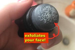 Hand holds a charcoal face exfoliator stick with product residue, labeled "exfoliates your face!"