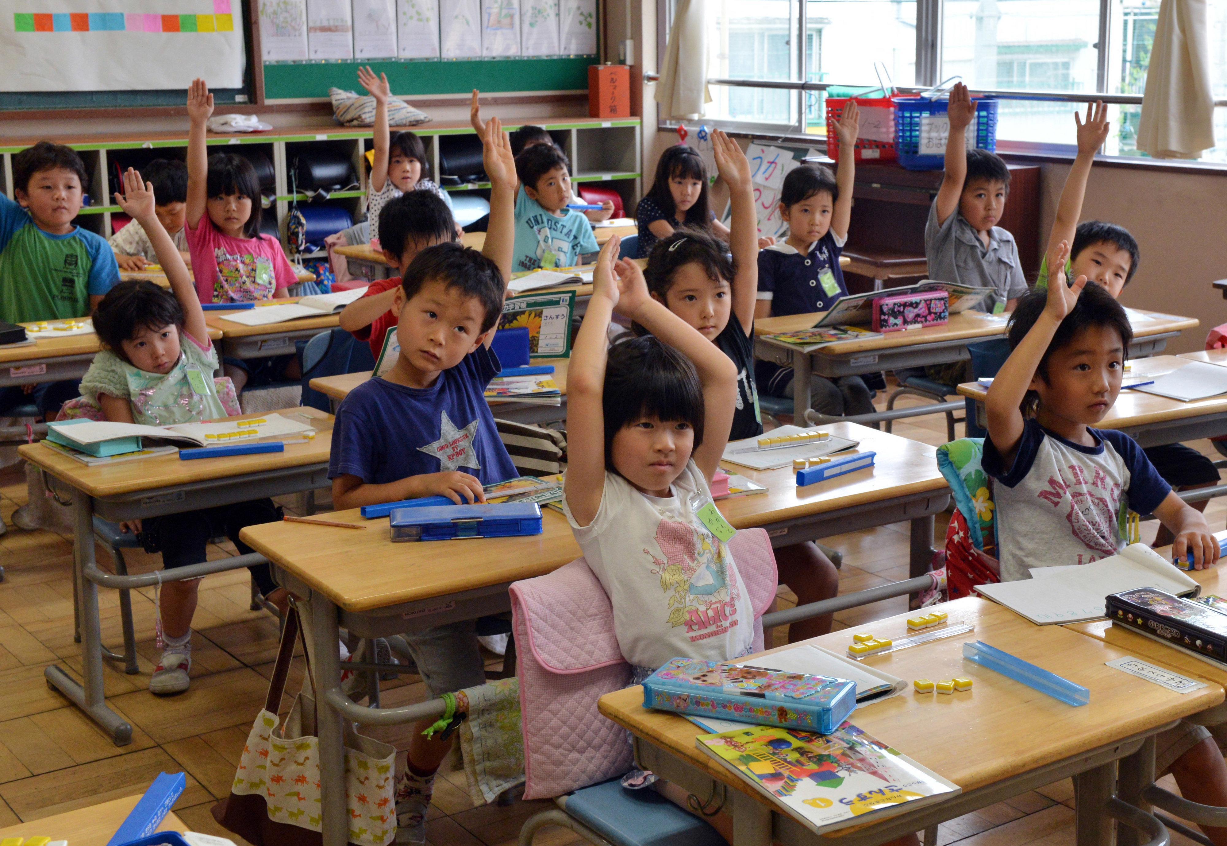Group of children raising hands in a classroom setting