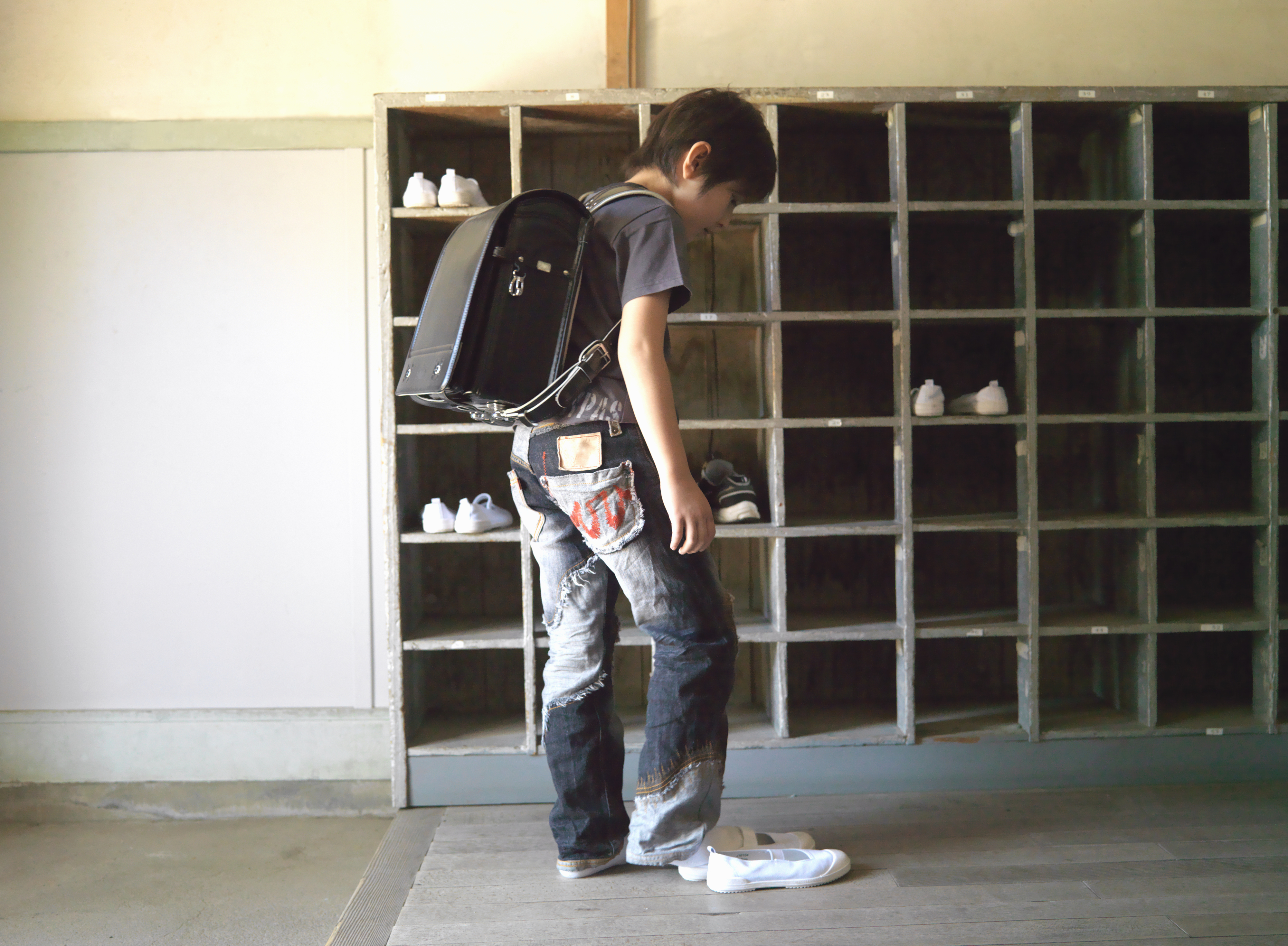 Child putting shoes in cubbyhole at a traditional Japanese inn, showcasing cultural etiquette