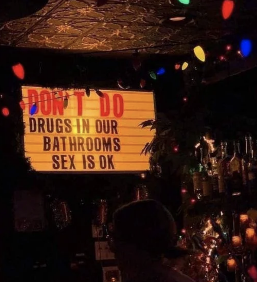 Sign in a bar reads &quot;DON&#x27;T DO DRUGS IN OUR BATHROOMS, SEX IS OK&quot; above a shelf of bottles