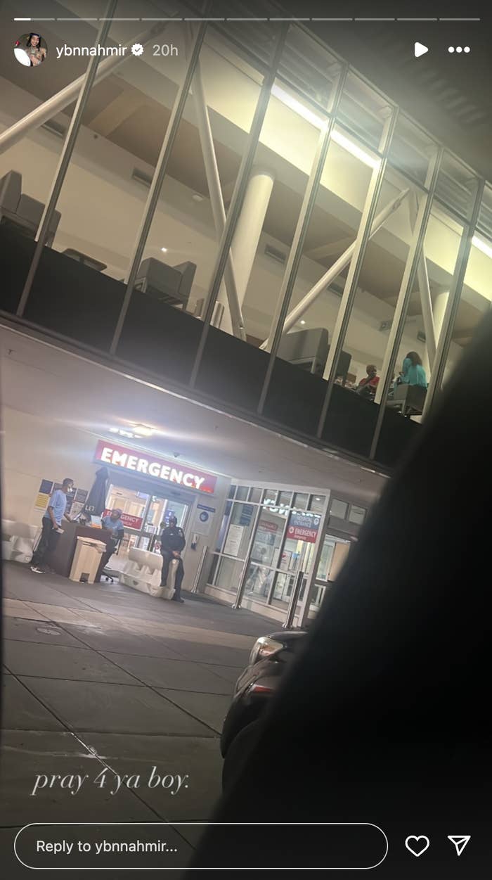 A view of an emergency room entrance at night with several individuals standing outside. Text overlay: &quot;pray for ya boy&quot;