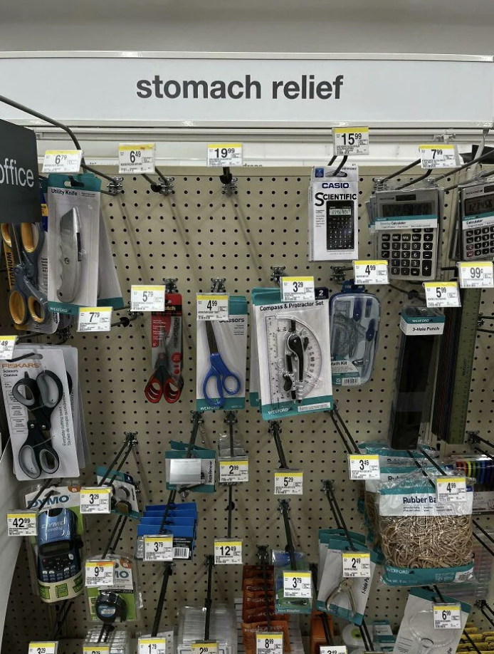 Store shelf with assorted office supplies under a &quot;stomach relief&quot; sign