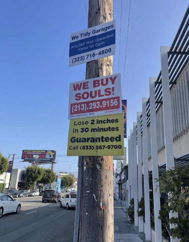 Multiple humorous signs on a pole offering services such as &quot;We Buy Souls&quot; and &quot;Lose 2 inches in 30 minutes, Guaranteed.&quot;