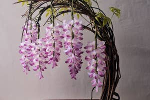 盆栽のスタイルで配置された紫の花と緑の葉を持つ植物。木の台の上にあります。