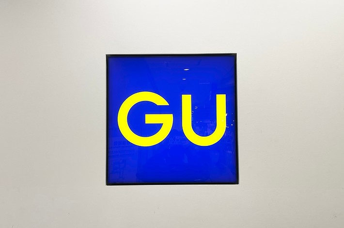 Artwork featuring the letters &ldquo;GU&rdquo; in large font on a blue background, mounted on a wall