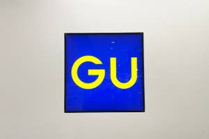 Artwork featuring the letters "GU" in large font on a blue background, mounted on a wall
