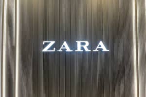 Storefront sign with 'ZARA' in white capital letters against a vertical striped background
