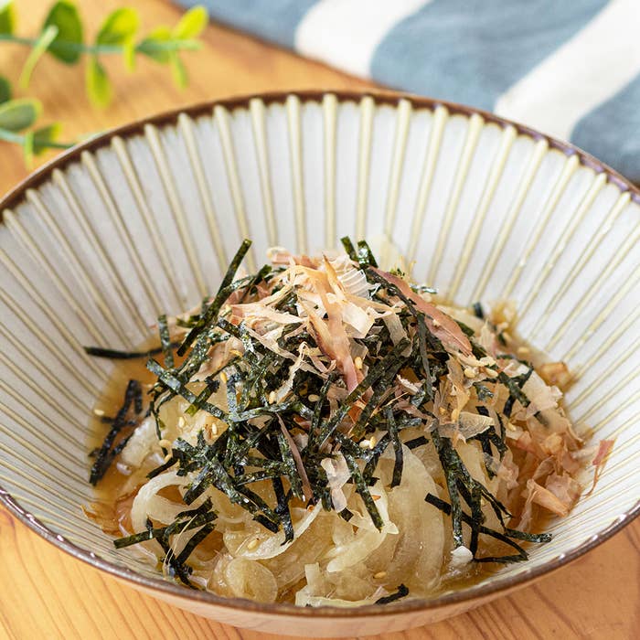 おわんに盛られたかつおぶしとのりがトッピングされた新玉ねぎのサラダ。