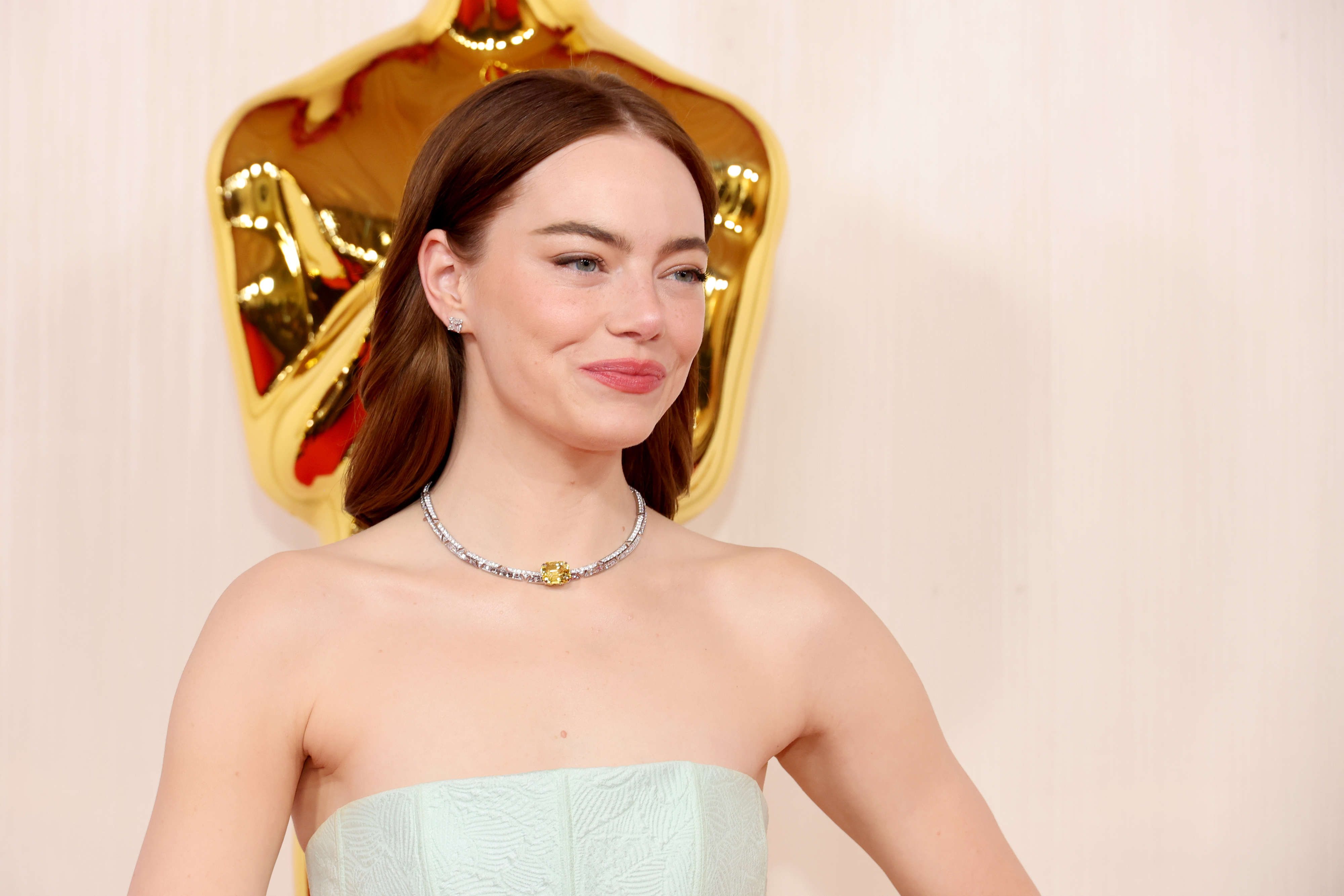 Emma Stone on red carpet wearing strapless gown and statement necklace