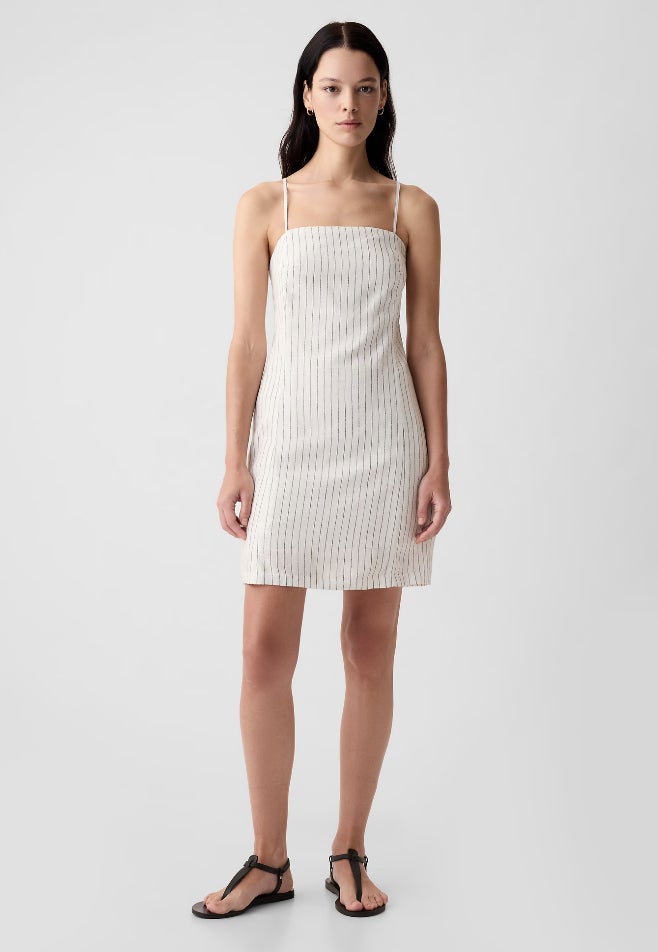 Model mengenakan mini dress berbahan linen bergaris ivory