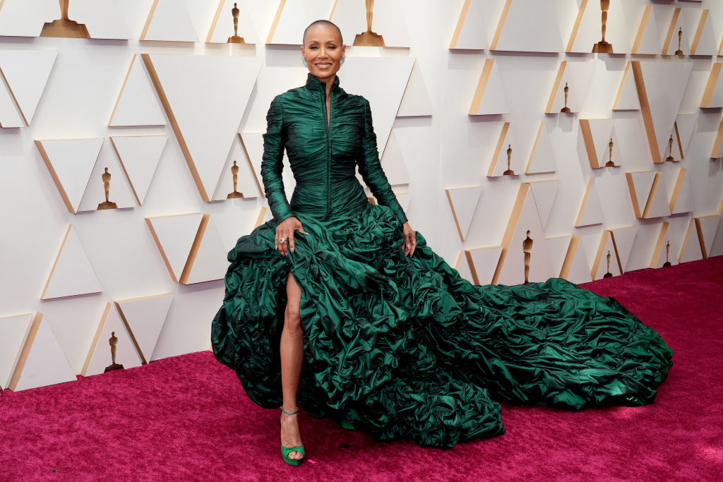 Jada Pinkett Smith wearing a dramatic, ruched green gown with a high neckline and long train on the red carpet