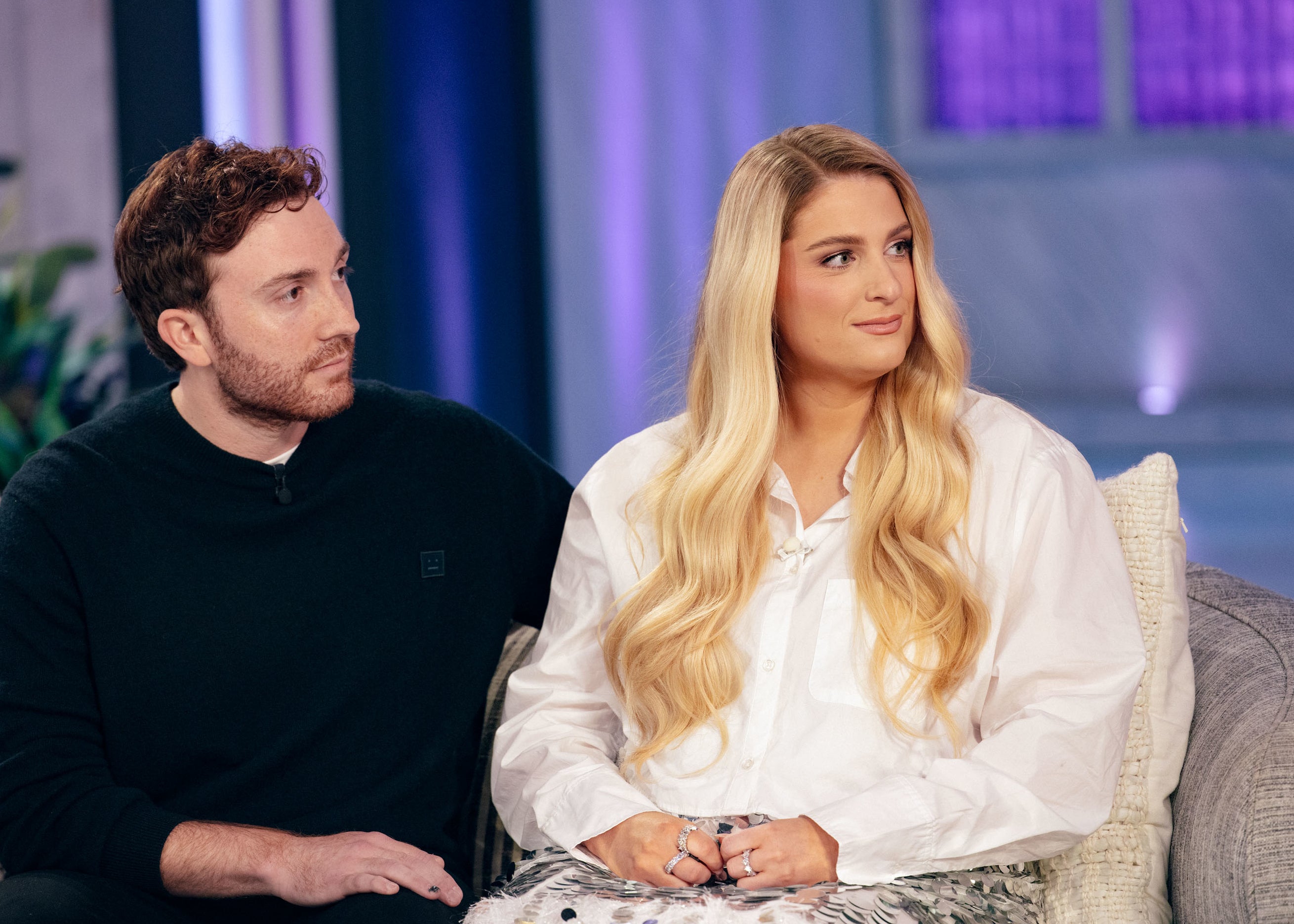 Meghan Trainor and Daryl Sabara seated on a couch during an interview, both looking towards the right