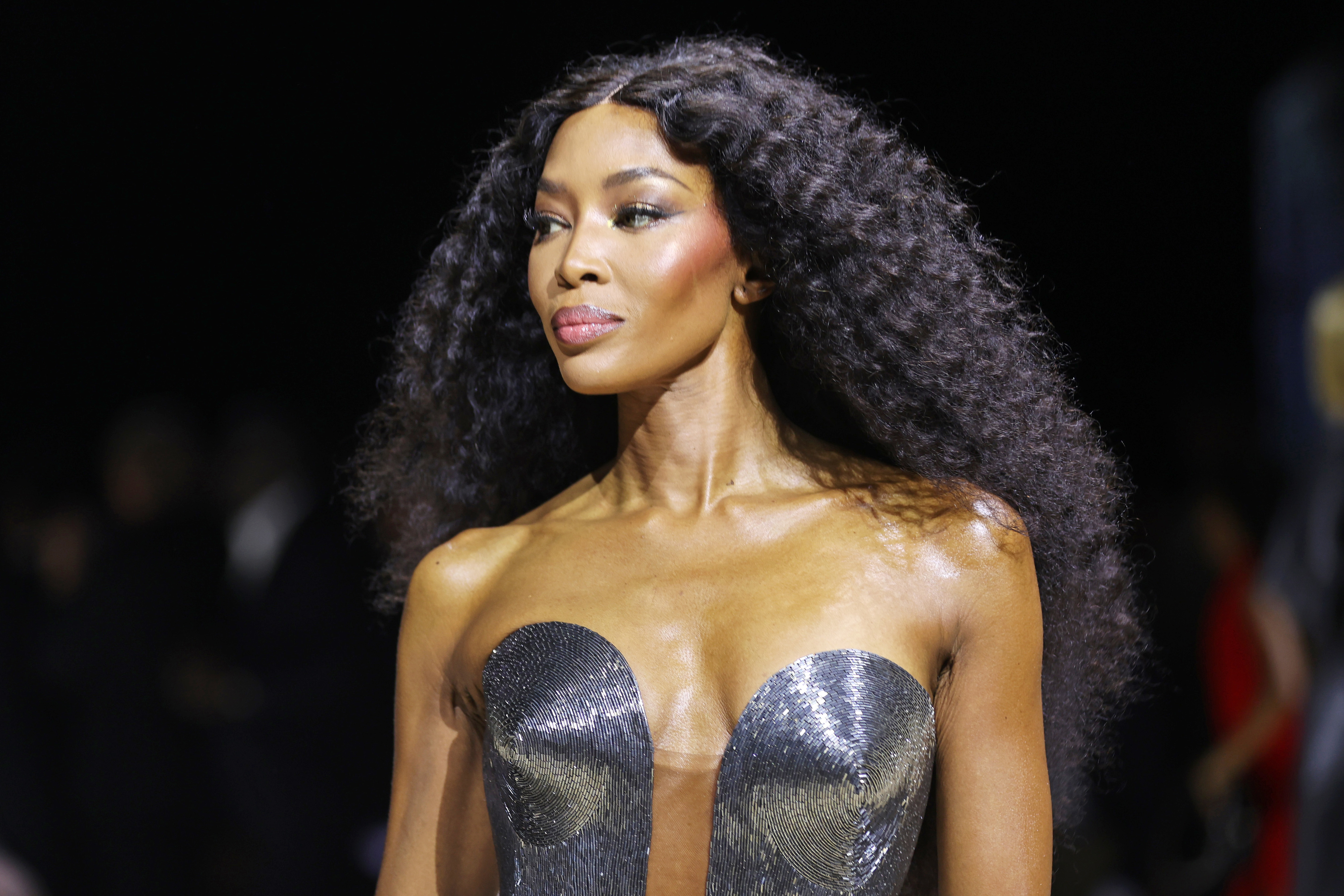 Naomi Campbell wearing a strapless metallic dress with voluminous, curly hair