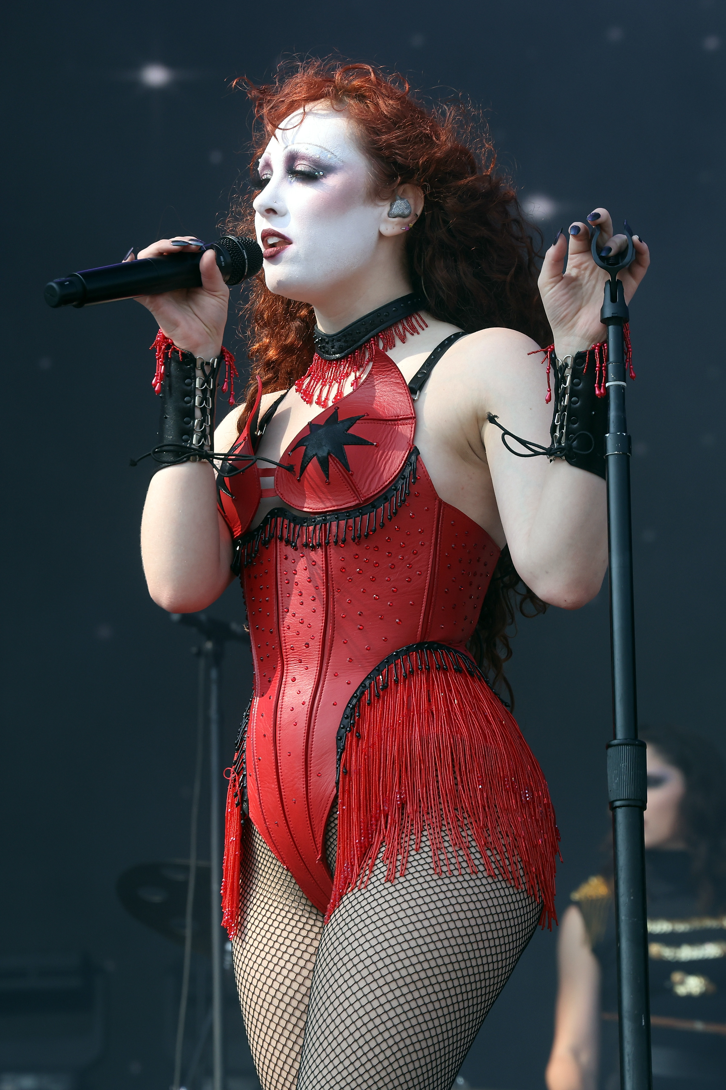 Singer Chappell Roan performs on stage in a corset outfit with fringe and fishnet stockings