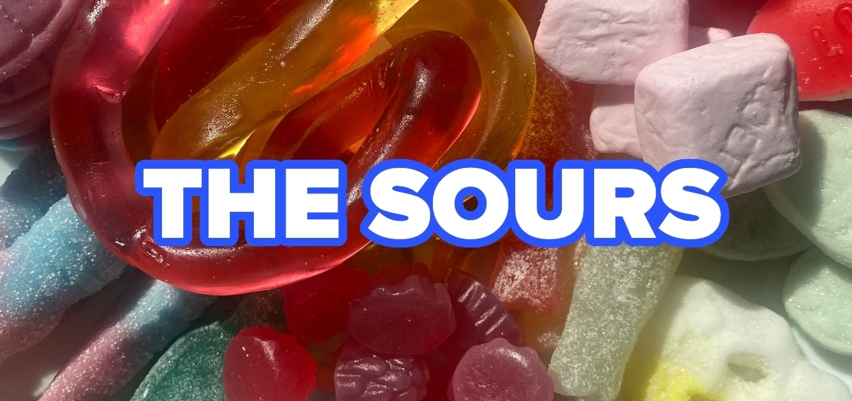 An assortment of sour candy including gummy rings, sugar-coated strips, and marshmallows with the text &quot;THE SOURS&quot; overlaying the image
