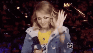 Carrie Underwood dances while holding a microphone at an NHL game