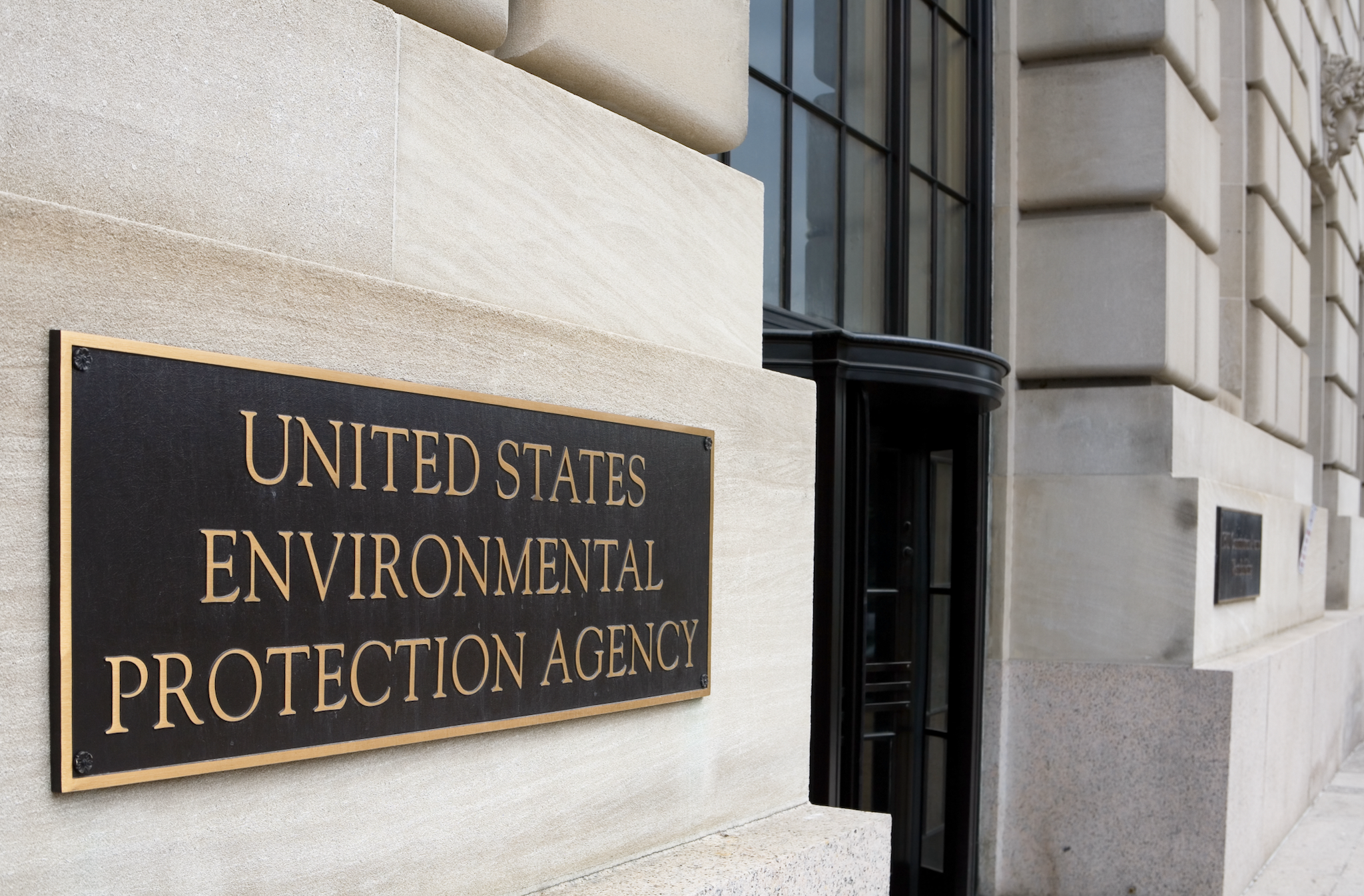 Sign reading "United States Environmental Protection Agency" on the exterior of a building with stone walls and large windows