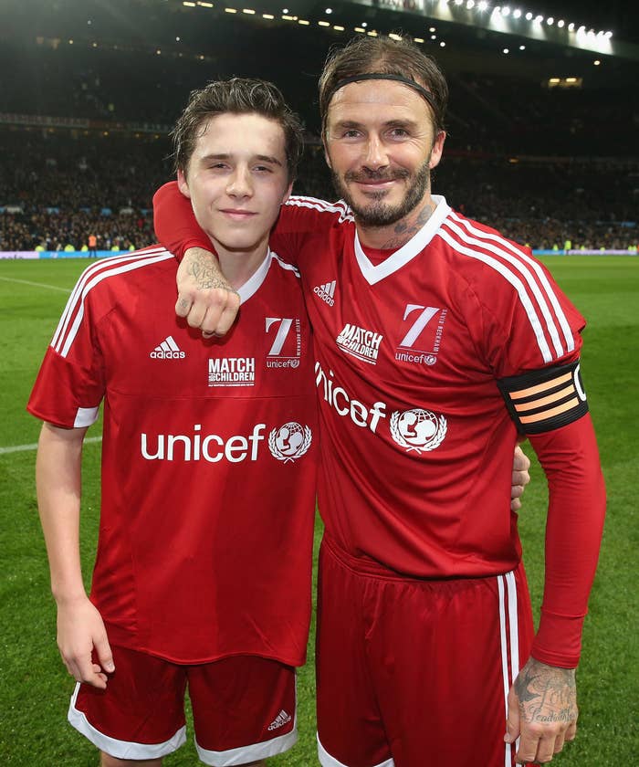 David Beckham and Brooklyn Beckham in UNICEF soccer jerseys, standing together on a soccer field during a match event