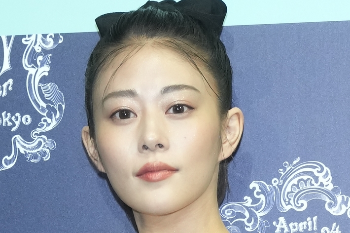 女性がフォーマルなイベントに参加している写真。シンプルなドレスを着て髪をアップスタイルにしている。名前は不明。