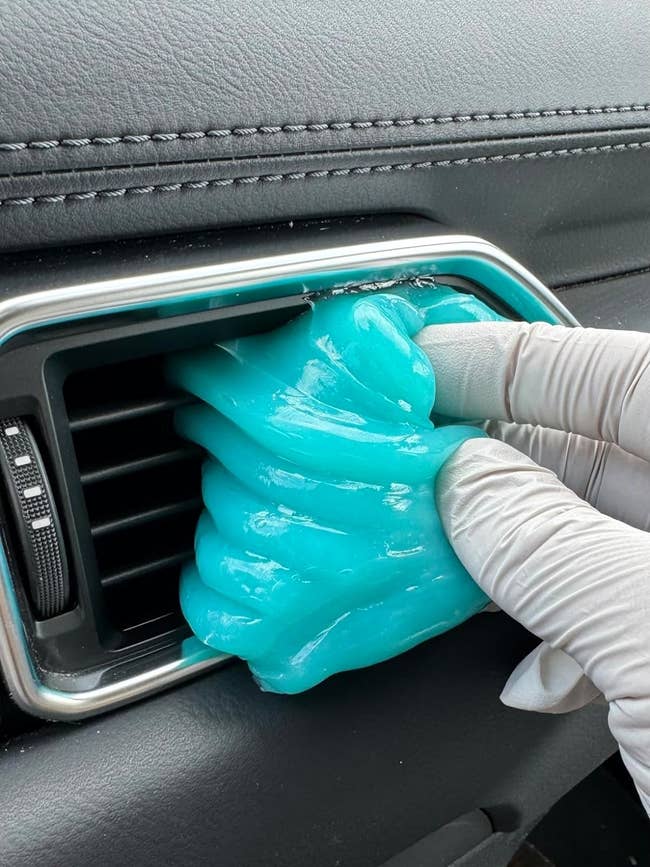 A idiosyncratic wearing gloves cleans a car aerial vent with bluish cleaning gel