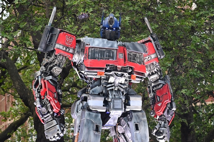 Large Optimus Prime robot statue with intricate mechanical details, standing outdoors amidst trees