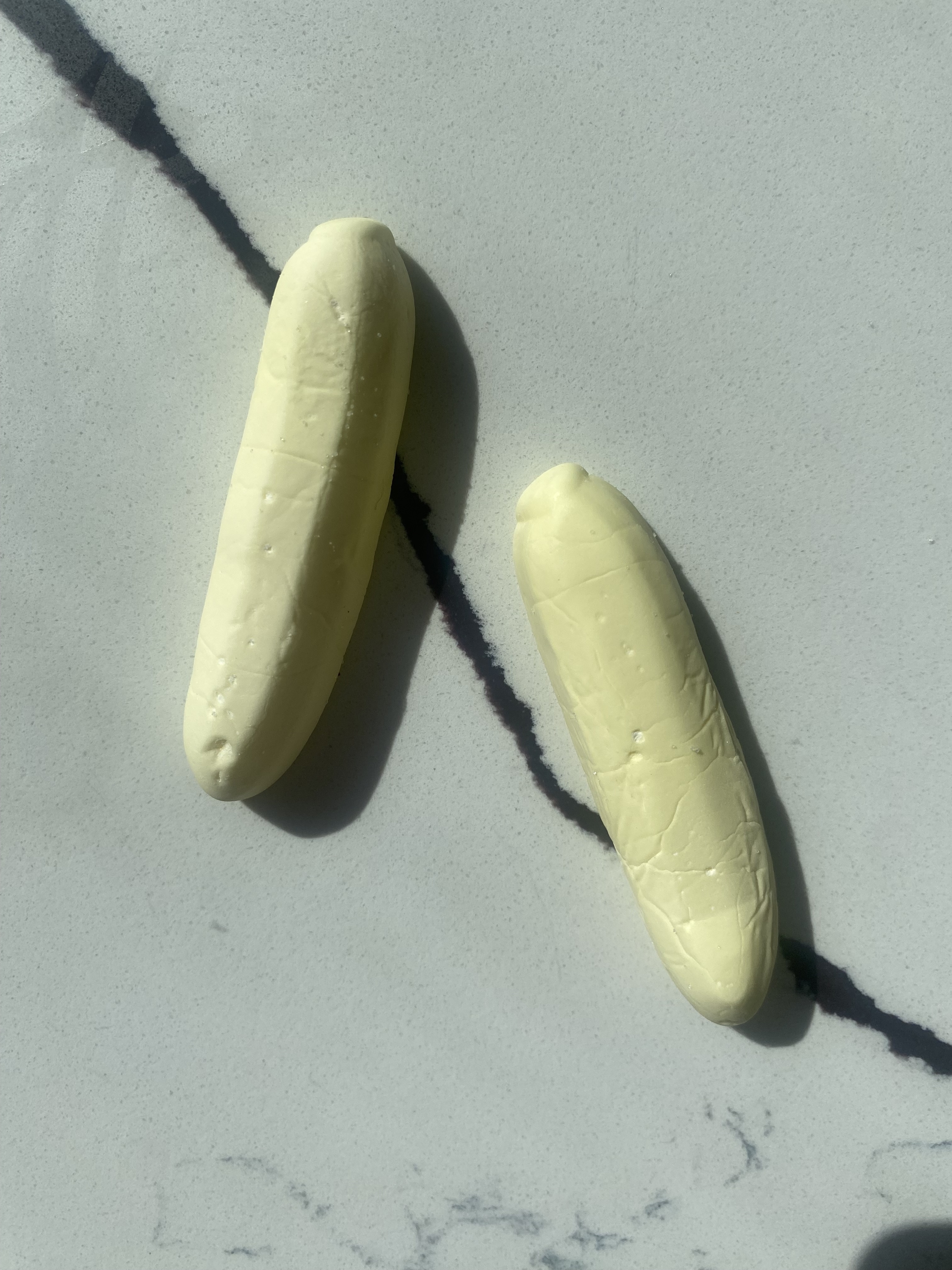 Two banana-shaped marshmallows placed on a marble surface