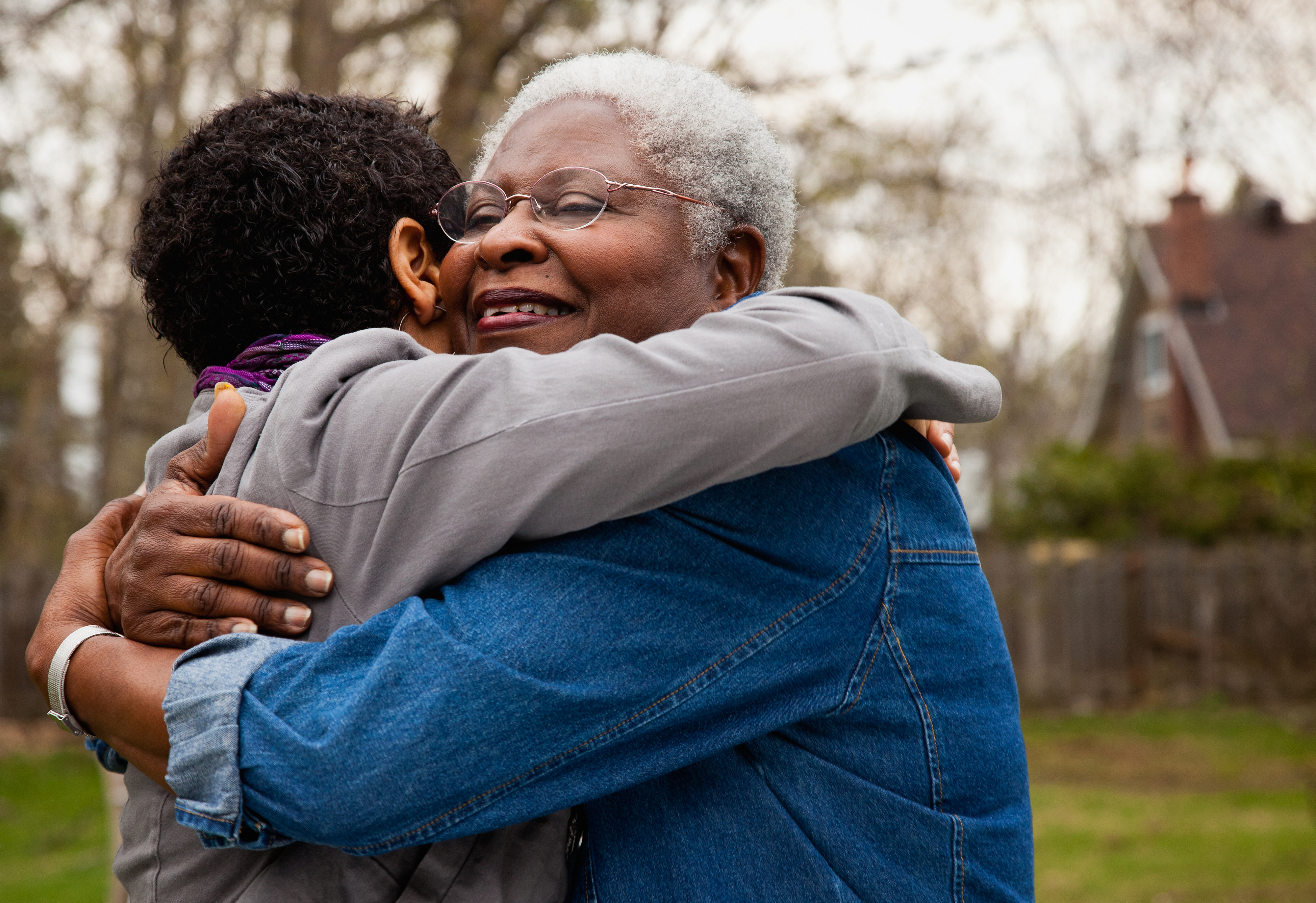 Two people embrace outdoors in a warm hug. Their faces are not visible