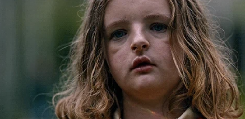 Close-up of girl with wavy hair looking ahead, a scene from the movie Hereditary featuring the character Charlie Graham
