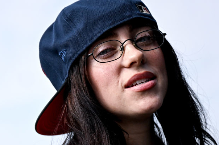 人物が眼鏡とキャップを着用してカメラを見ている。