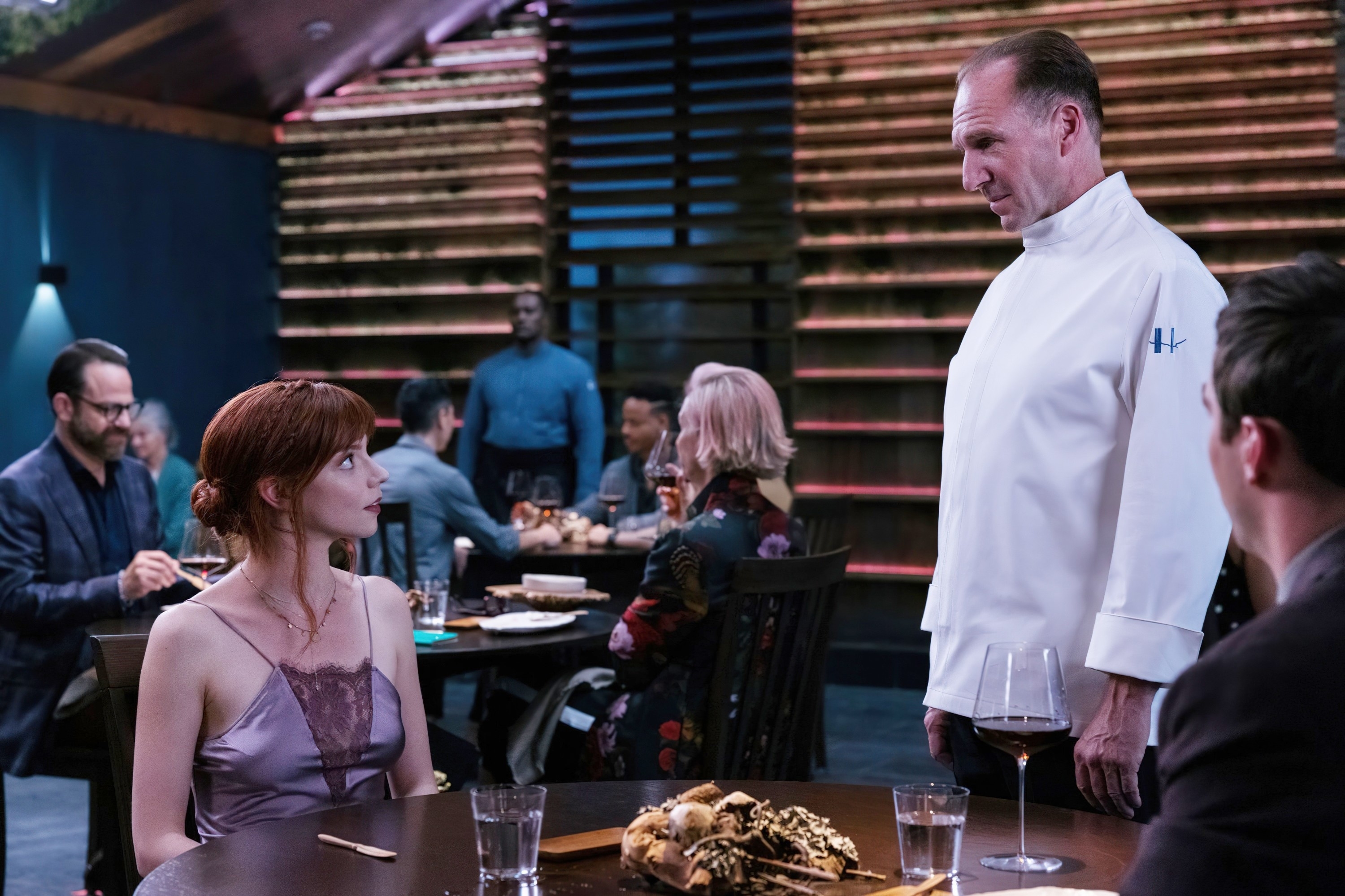 Anya Taylor-Joy, Ralph Fiennes, Nicholas Hoult at dining table in a restaurant in a scene from "The Menu"