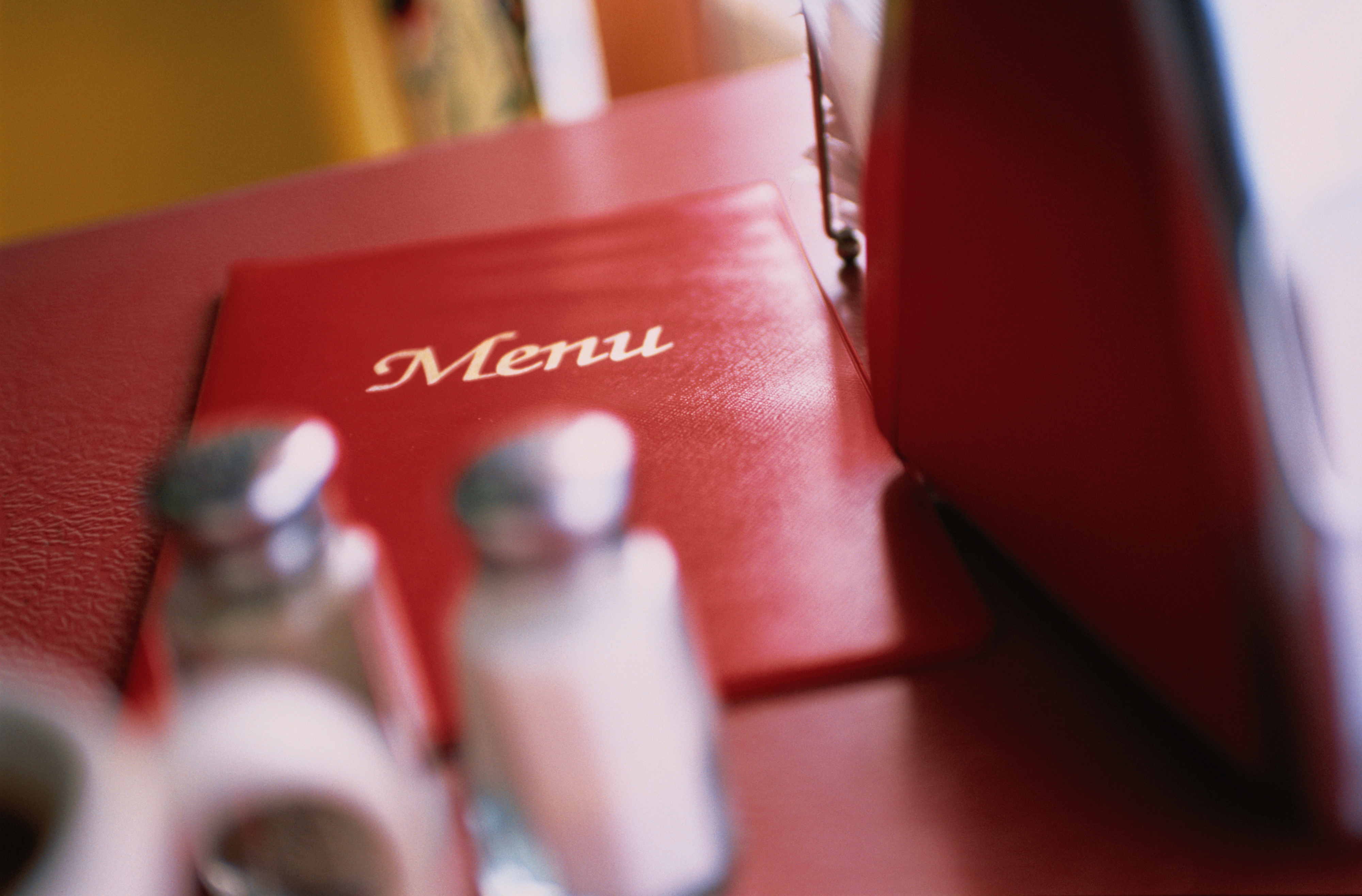 A close-up photo of a red menu on a restaurant table, with salt and pepper shakers in the foreground