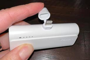 Hand holding a white portable battery with a built-in Lightning connector