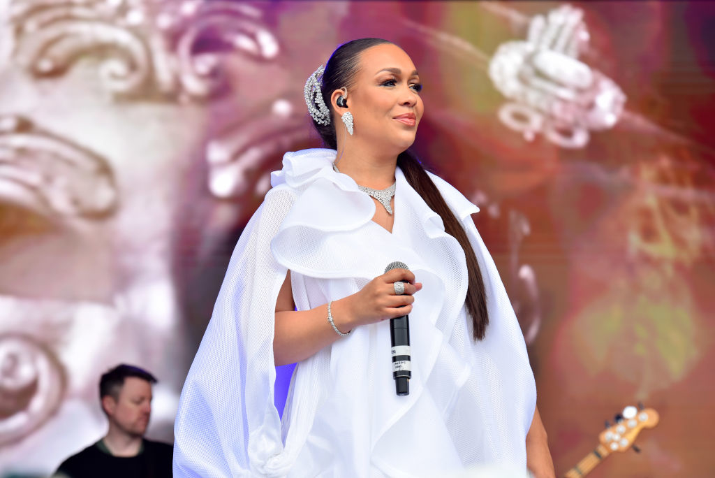 Alicia Keys performs on stage wearing an elegant white dress with ruffled details and a statement hair accessory