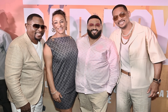 Martin Lawrence, guest, DJ Khaled, and Will Smith pose together at a red carpet event. Martin and Will wear stylish suits, while DJ Khaled wears a casual outfit