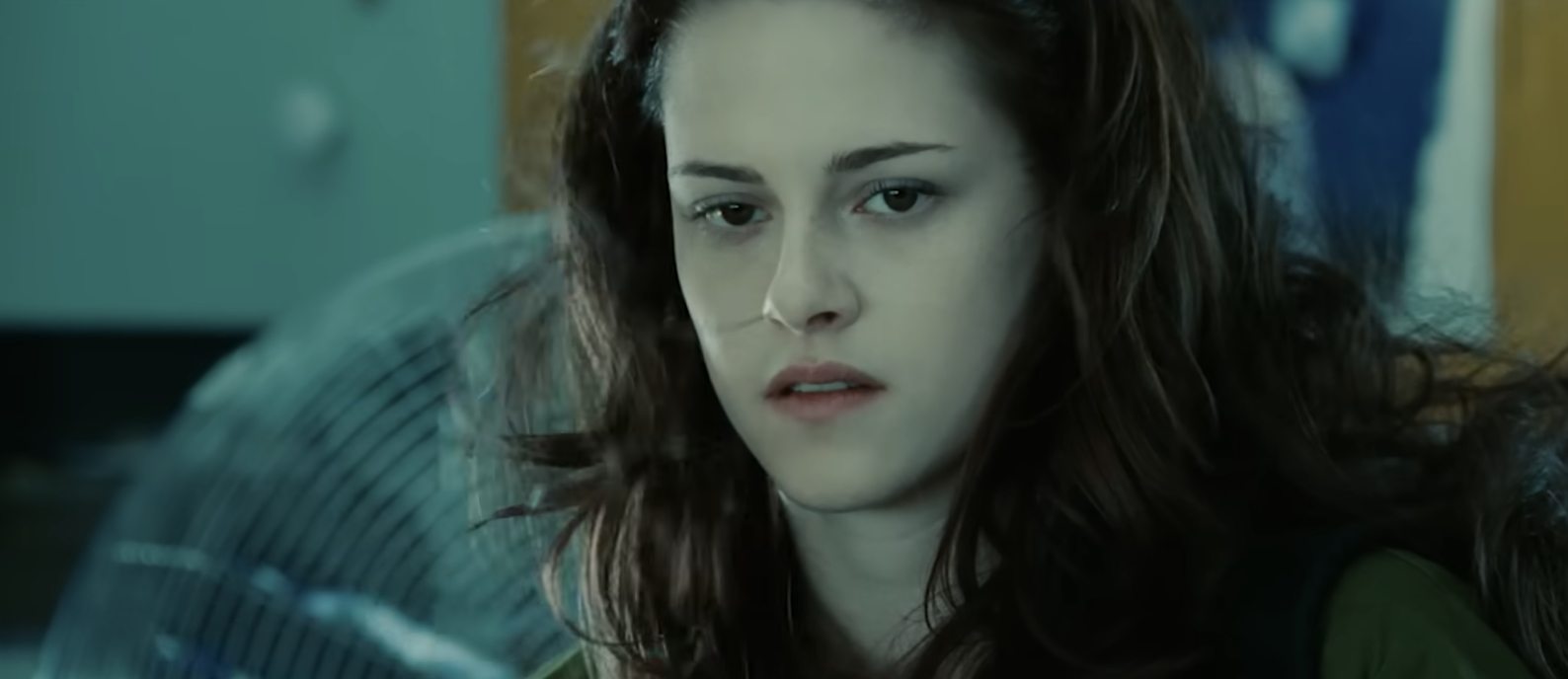 Kristen Stewart with a contemplative expression, appearing to be in a room with a large fan in the background