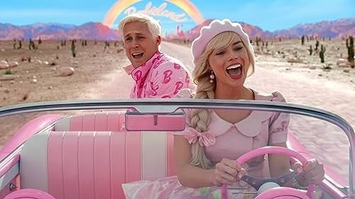 Ryan Gosling and Margot Robbie, dressed in pink 1950s-style clothing, ride in a pink convertible with a "Barbie Land" sign behind them in a desert setting