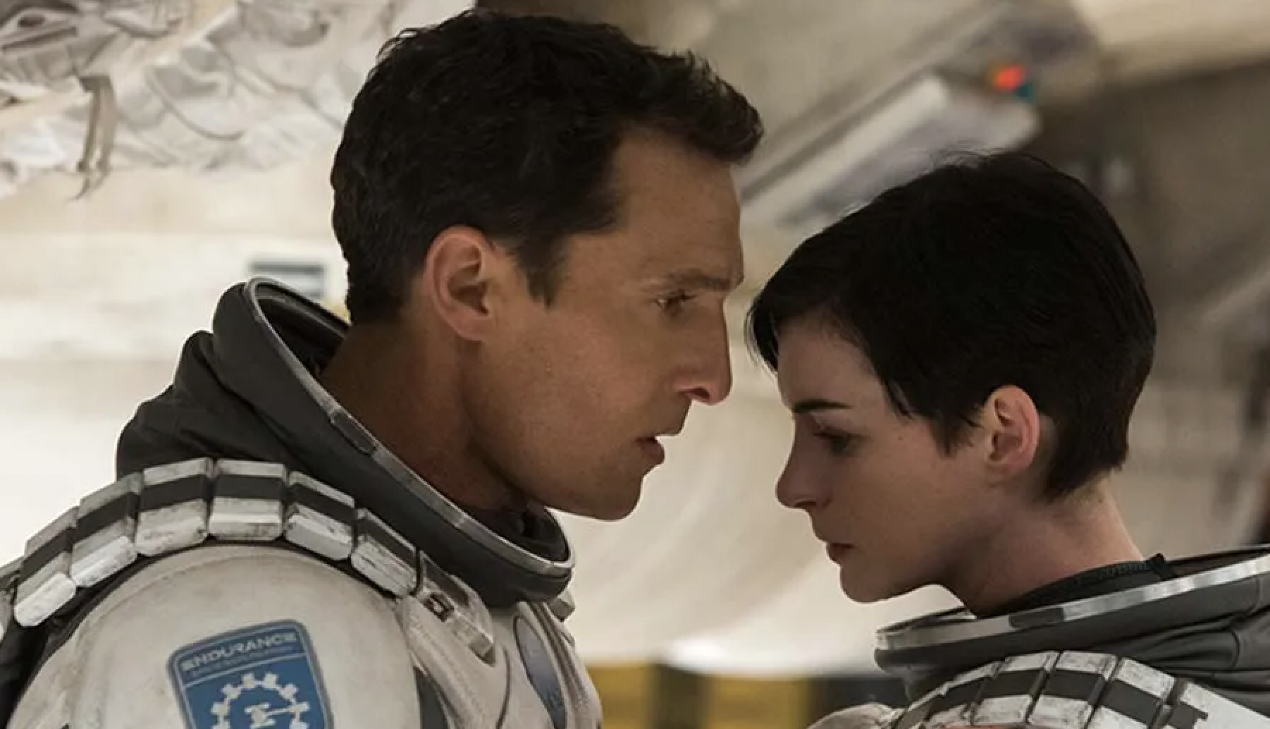 Matthew McConaughey and Anne Hathaway, in astronaut suits, facing each other closely in a scene from the movie "Interstellar."