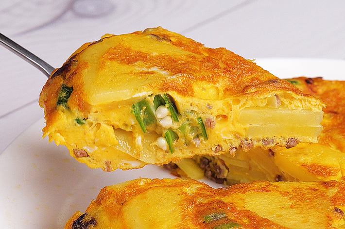 オムレツの一部がフォークで持ち上げられており、中に野菜や具材が見える。