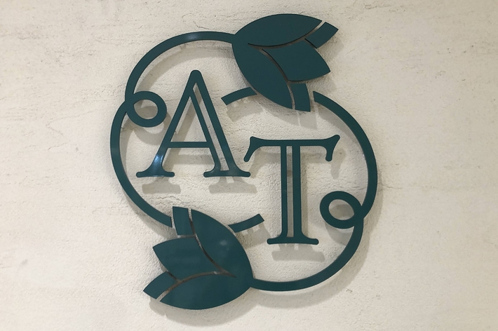壁に「A T」と書かれた葉っぱのデザインのロゴ。