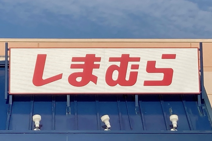 Storefront with sign featuring Japanese characters, indicating a Shimamura location. A handicap parking symbol is visible in front