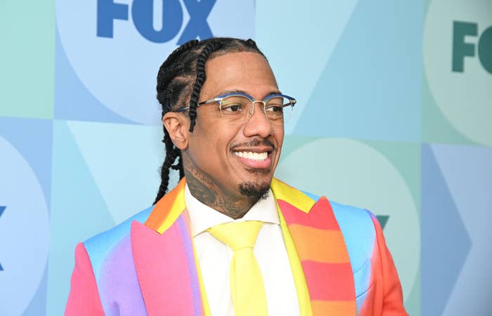 Nick Cannon wearing a vibrant, multi-colored suit with a tie poses on the FOX blue-carpet event backdrop