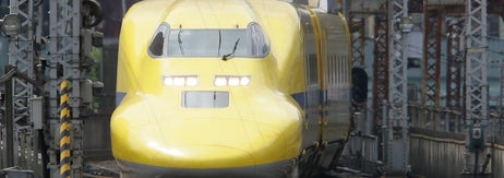 黄色い新幹線が線路を走行中。日本の高速鉄道システムの一部。