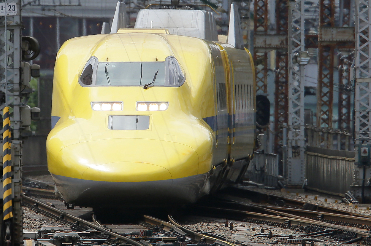 黄色い新幹線が線路を走行中。日本の高速鉄道システムの一部。