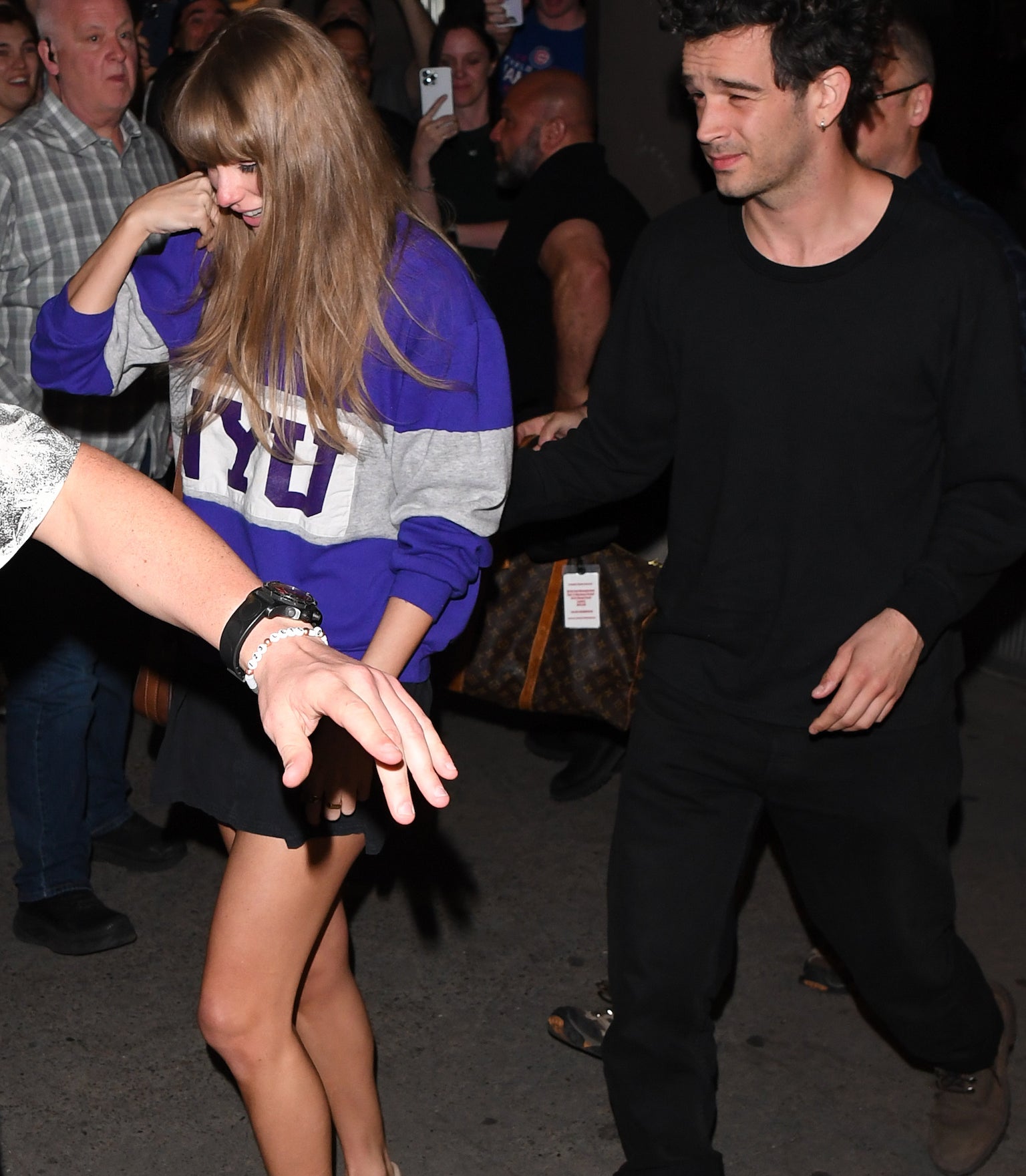 Taylor Swift, wearing a casual outfit with an NYU sweatshirt, walks with Matty Healy