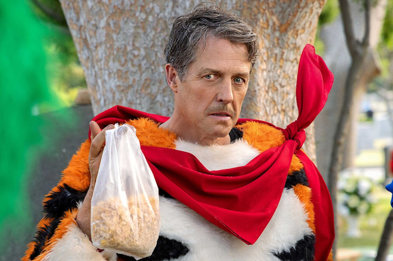 Hugh Grant dressed in a Tony the Tiger costume, holding a bag of cereal