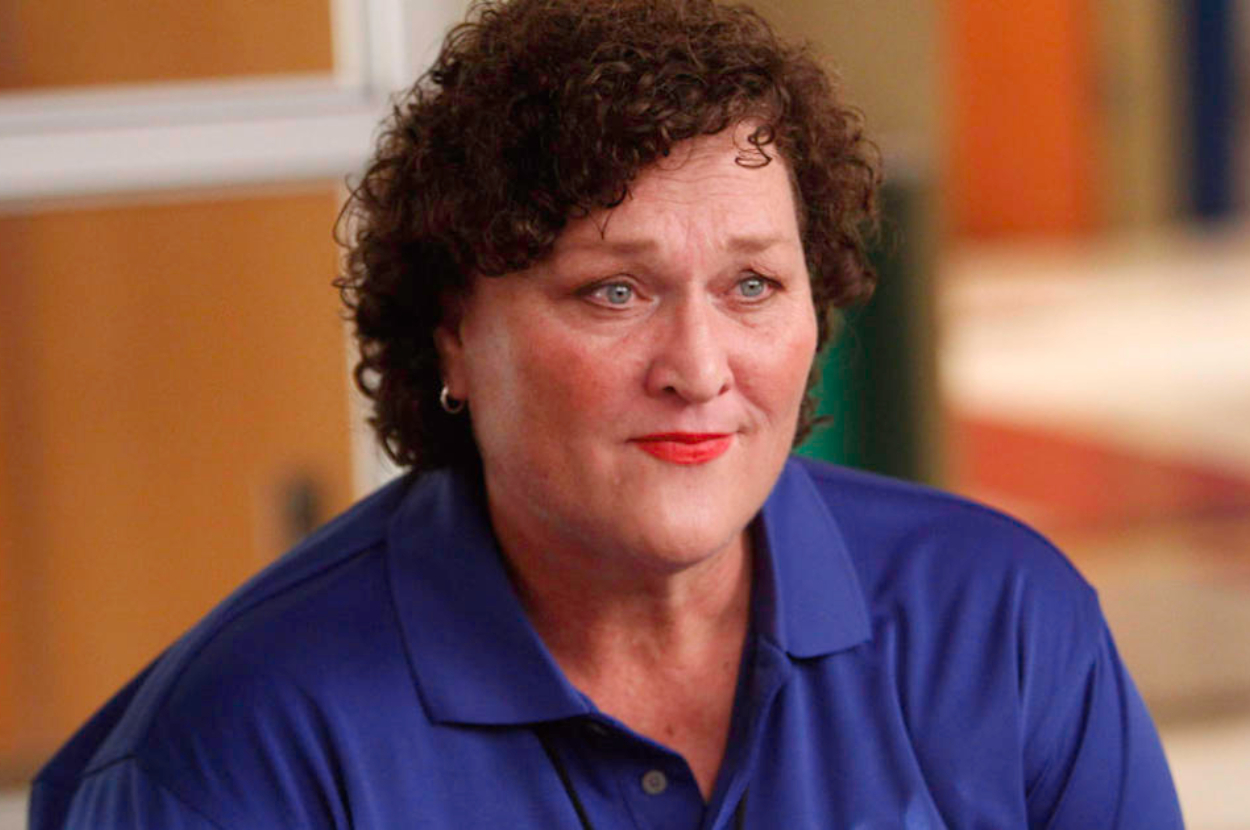 A person with short curly hair and wearing a blue polo shirt, appears to be in a thoughtful or serious moment