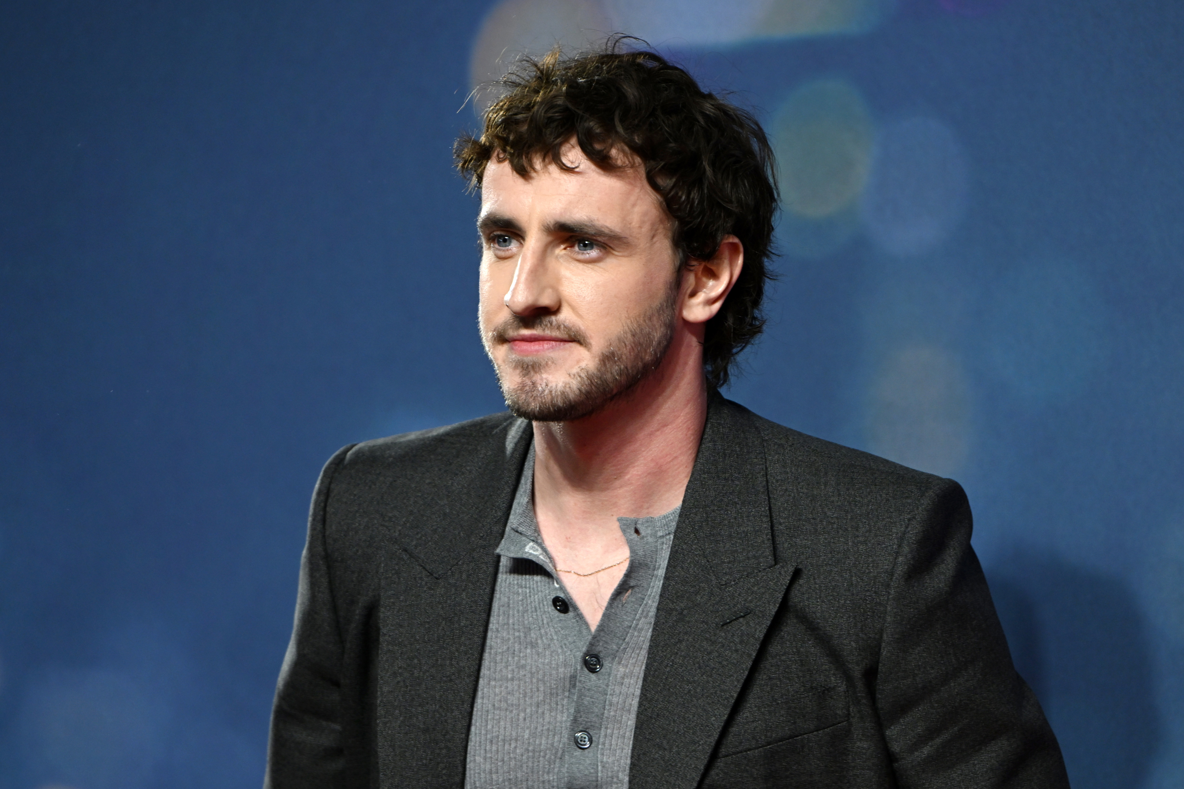 Paul Mescal at an event, wearing a grey shirt under a dark blazer