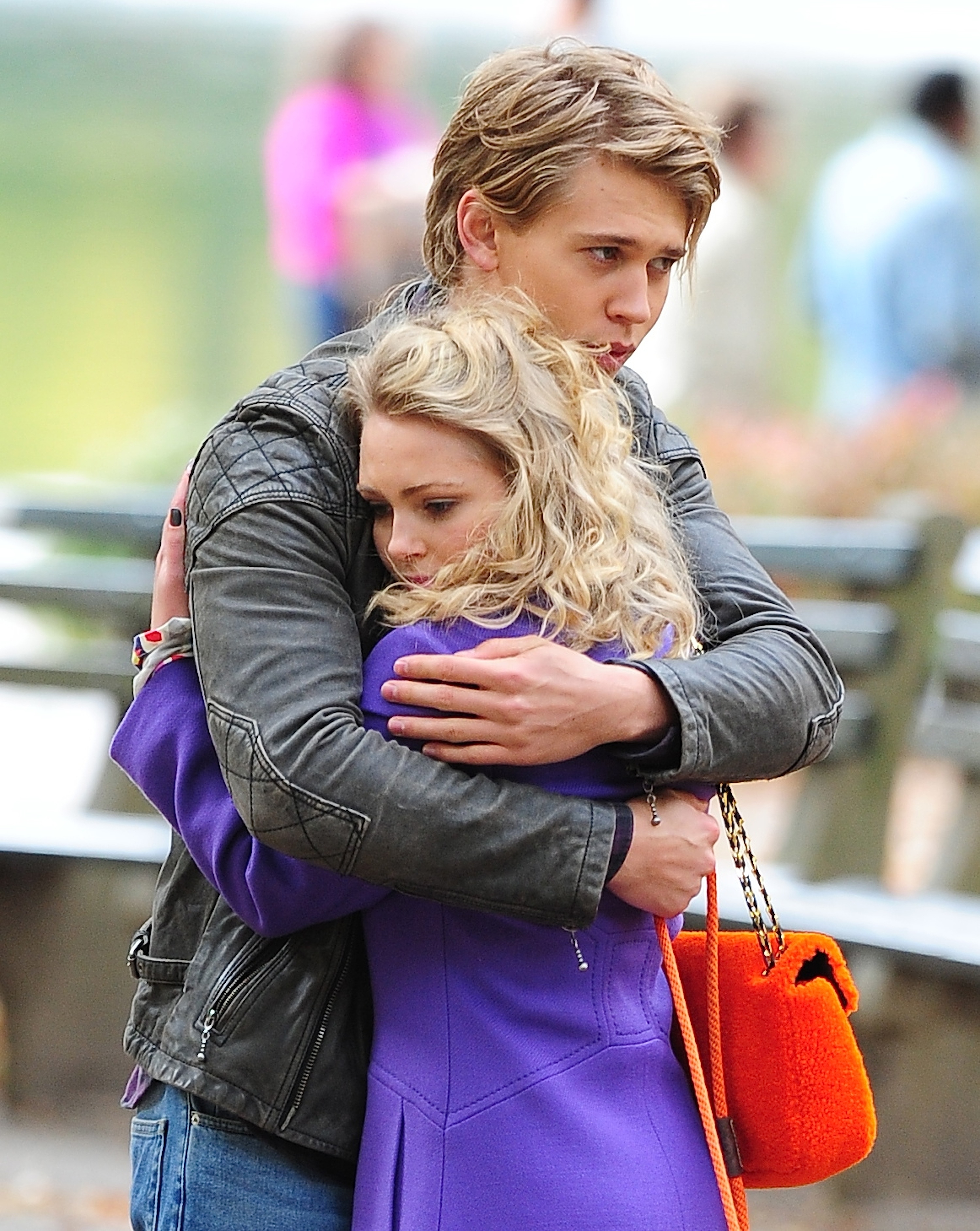 Austin Butler and AnnaSophia Robb hugging outdoors, with AnnaSophia wearing a stylish coat and orange purse