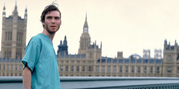 Cillian Murphy stands in front of the Palace of Westminster wearing a hospital gown, looking concerned