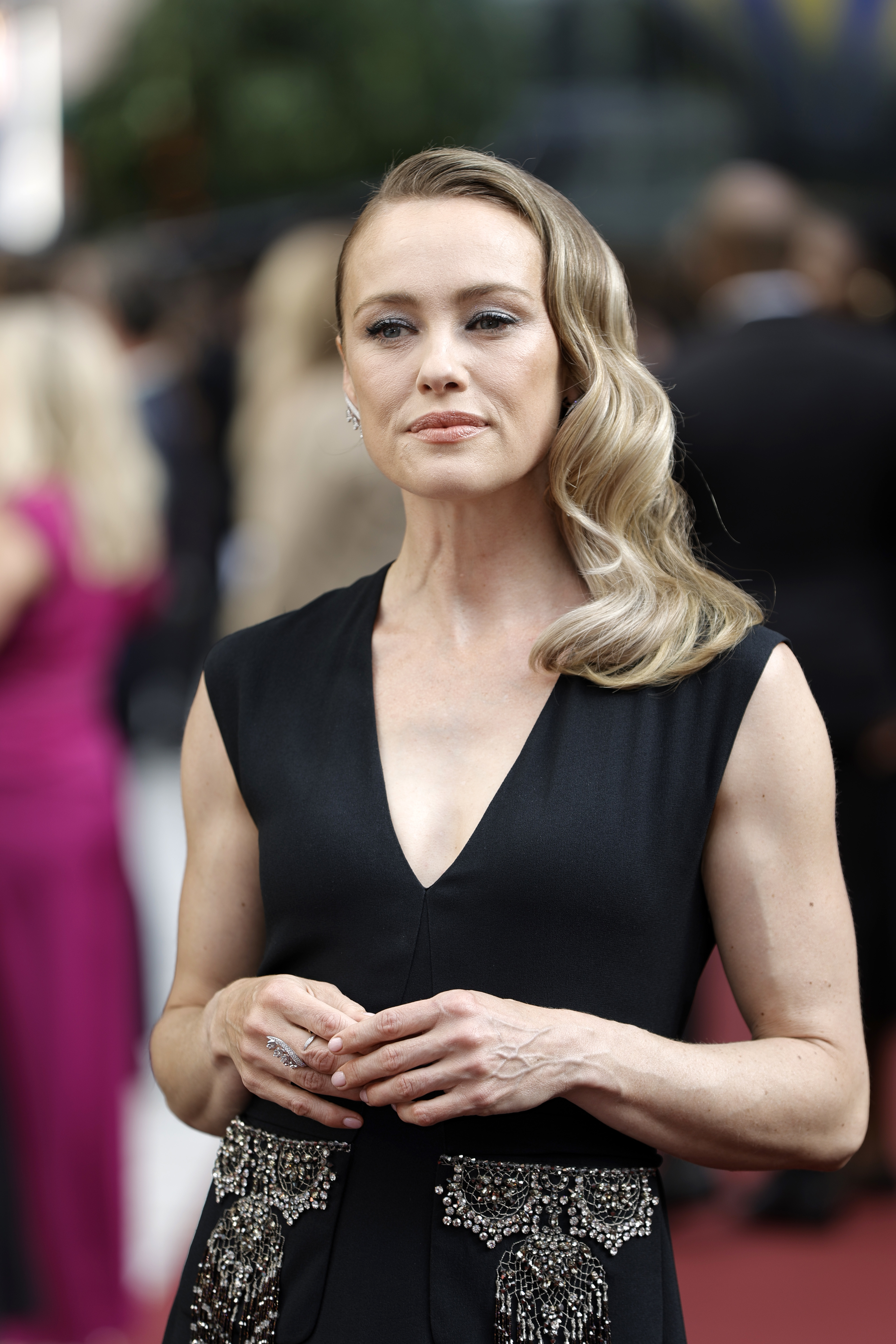 Hannah New with wavy hair poses on a red carpet in a sleeveless dress with intricate embellishments